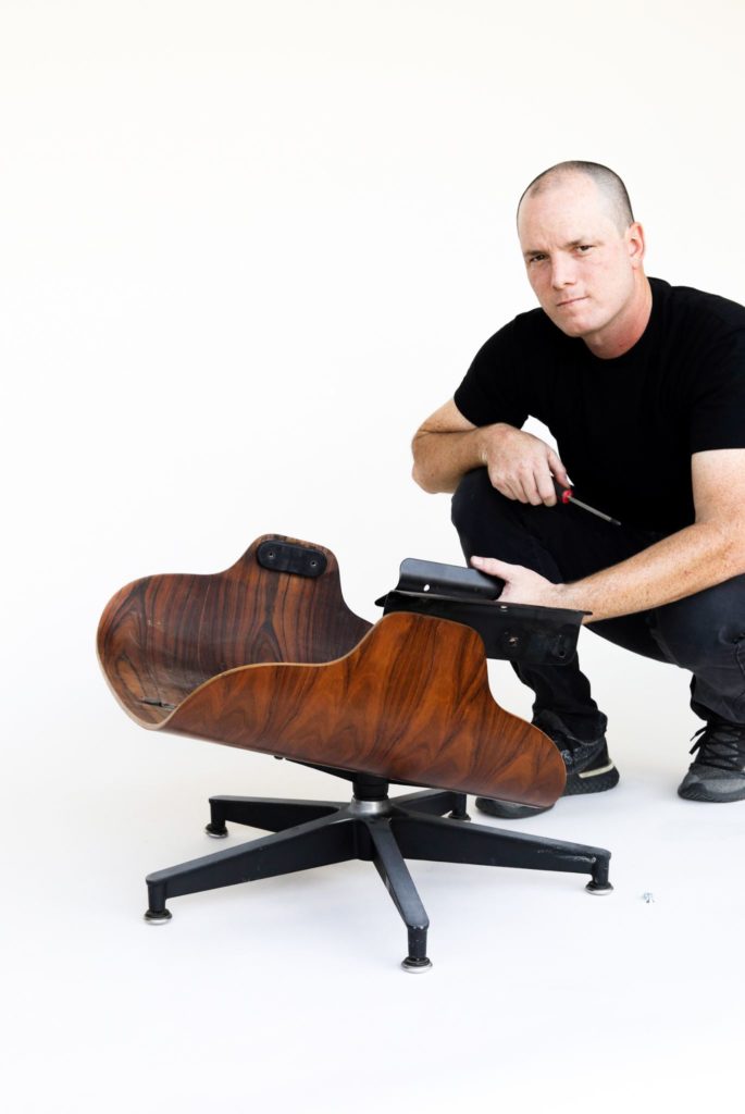 Hobbs working on an Eames Chair against a white backdrop