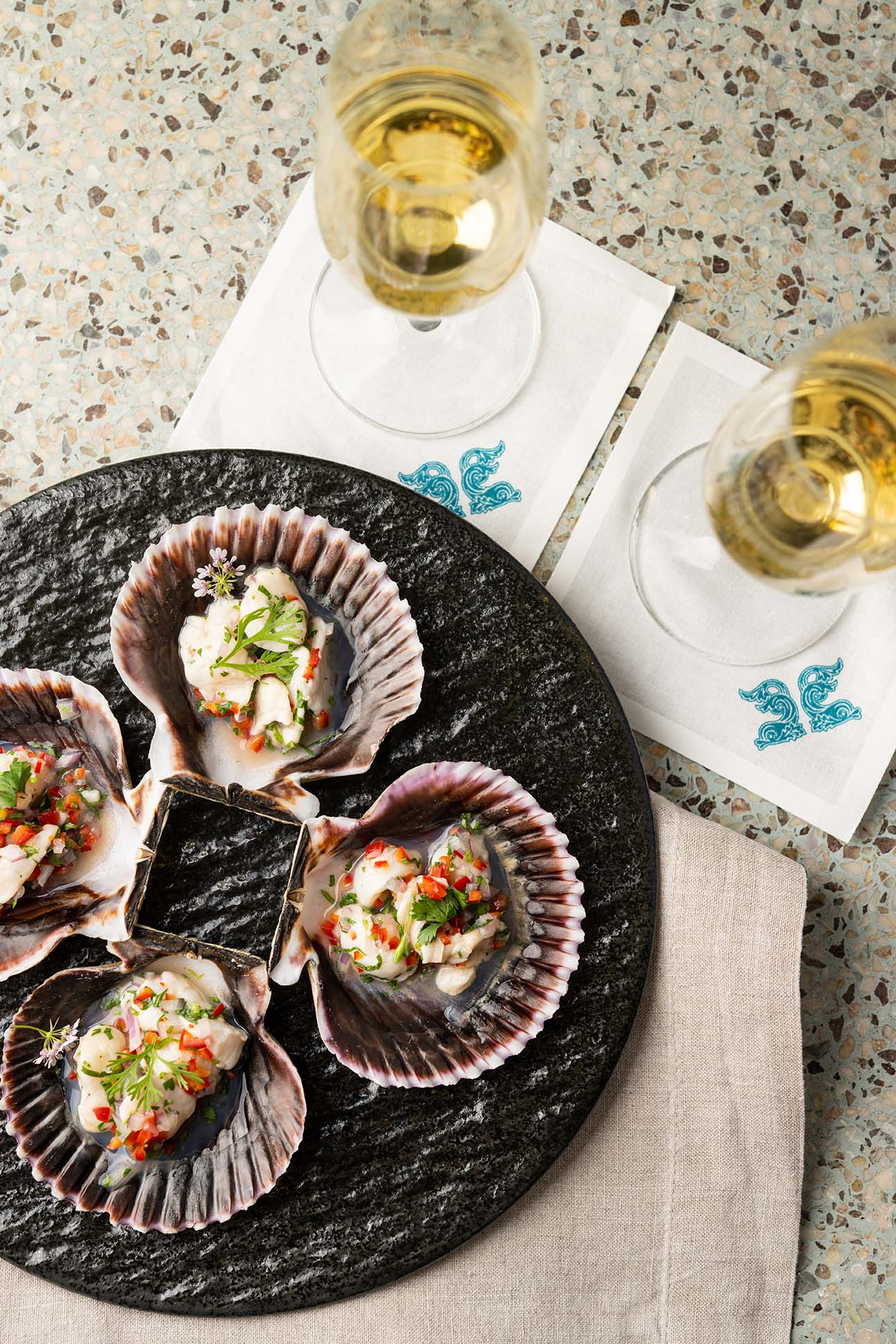 A fresh plate of seafood paired with two glasses of wine. A delicious meal contrasting the ocean breeze.