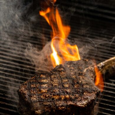 Steak being fired onto the grilled to cook.