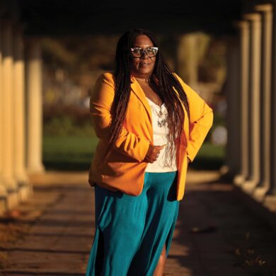 a person in a yellow jacket and blue skirt walking on a walkway