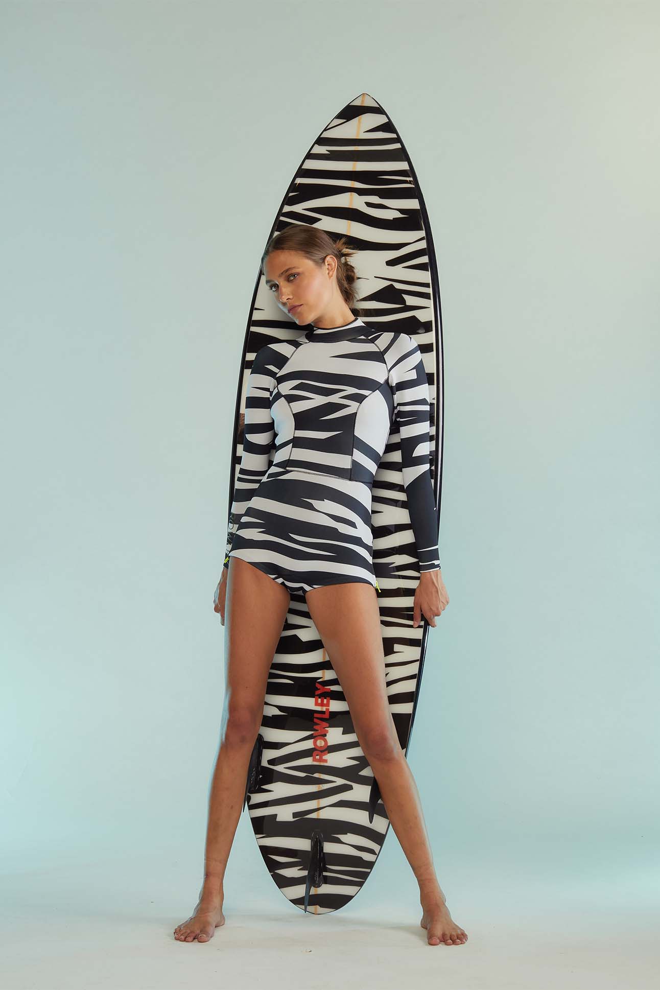 a person in a zebra print swimsuit leaning on a surfboard